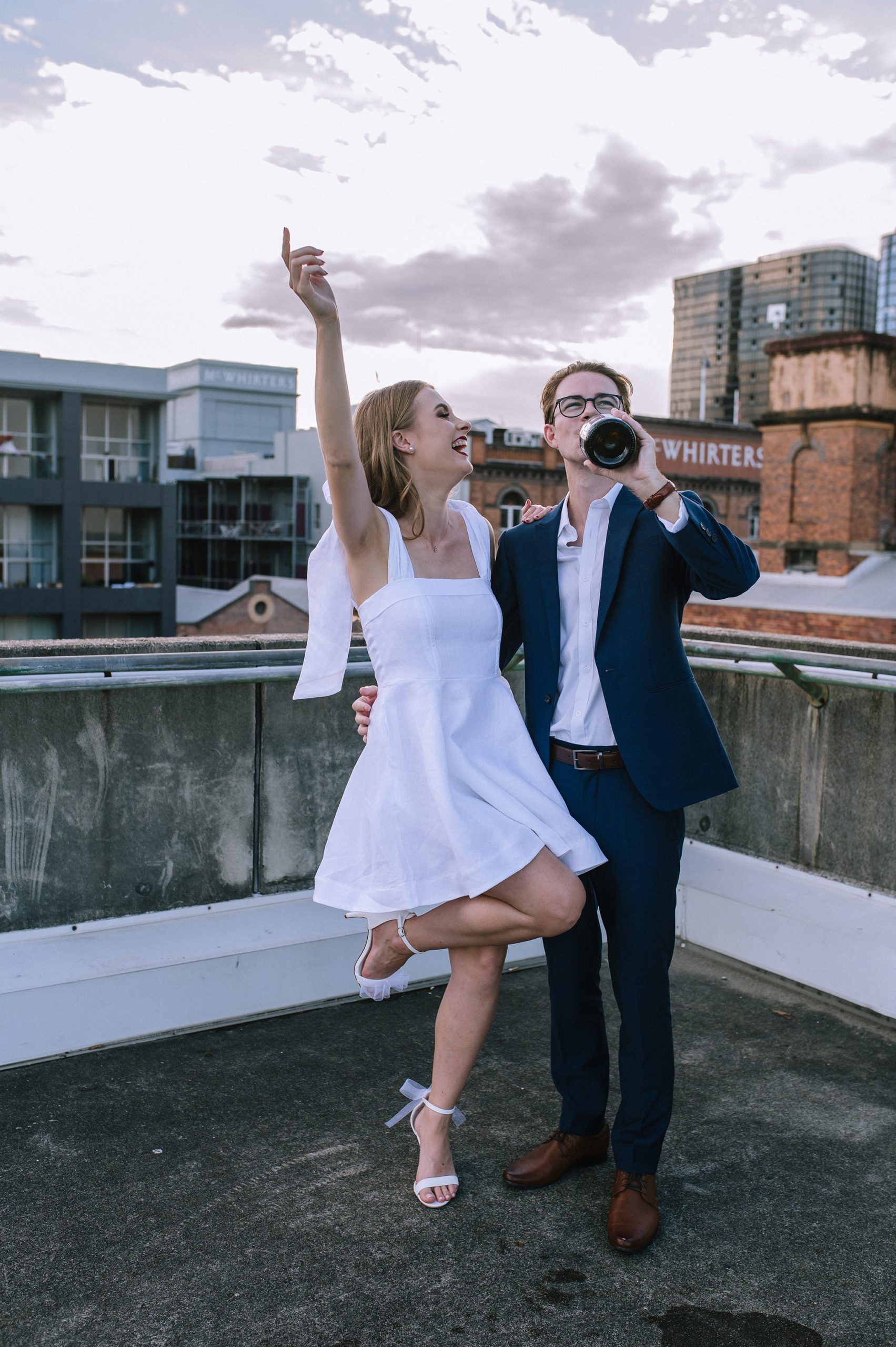Engaged couple popping champion on rooftop during their engagement photography session; with Tayla Jayne Photography