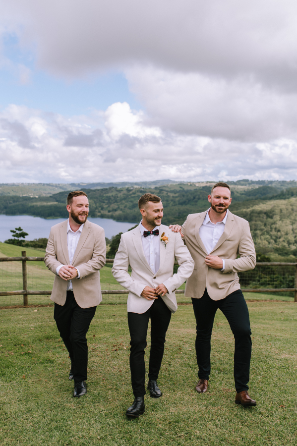 Groom adjusting suit with lake views in the background