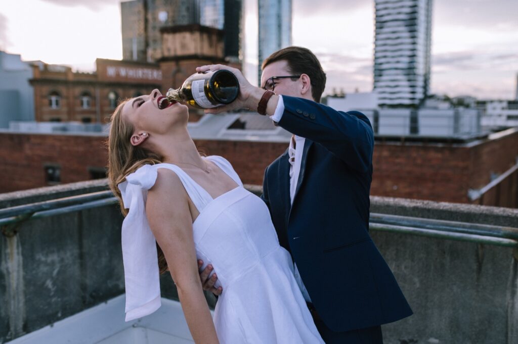 brisbane rooftop engagement session with couple popping champagne
