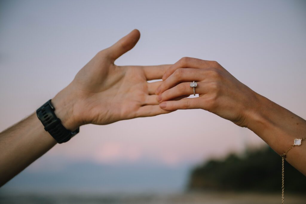 close up of couple holding hands with ring during engagement photography session