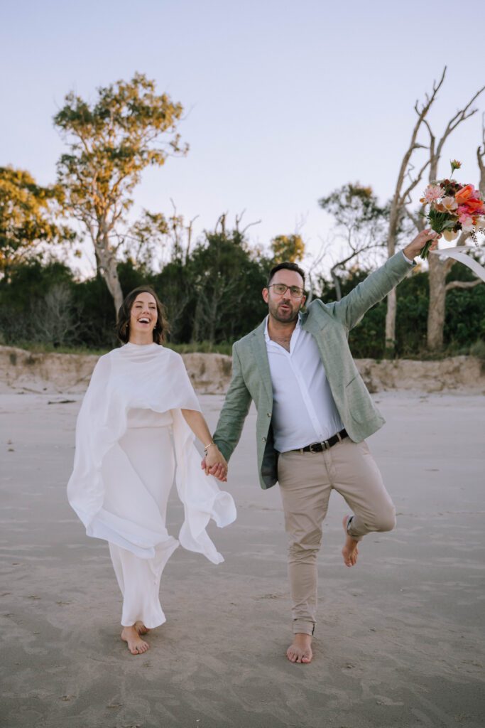 couple laughing and having fun on the beach after sunshine coast wedding ceremony