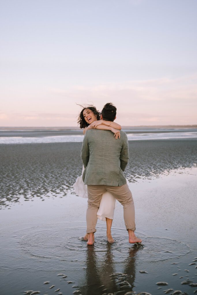 bride and groom hugging barefoot on the beach after sunshine coast wedding ceremony