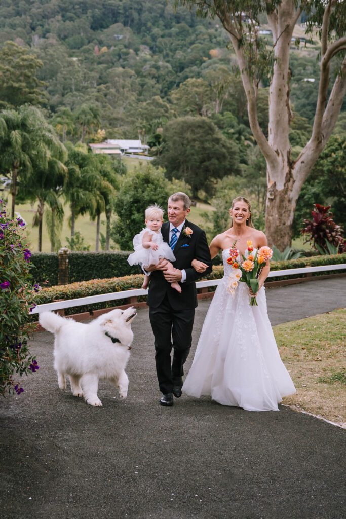 bride walking with dad and dog to the wedding ceremony 