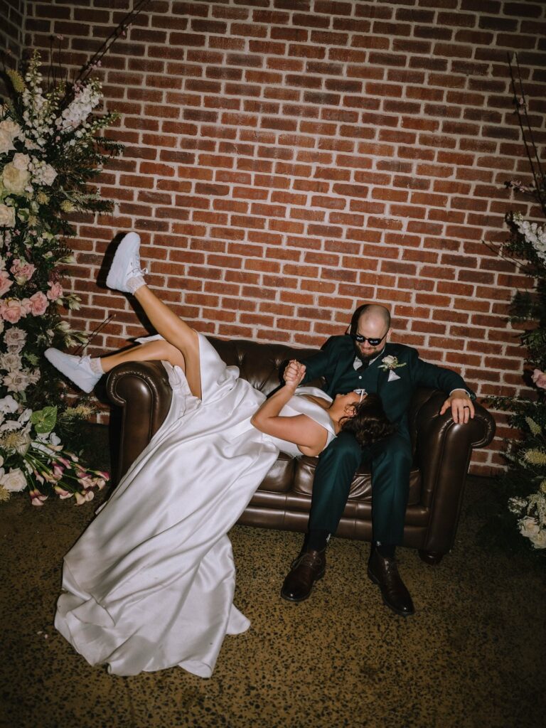 couple relaxing on leather chesterfield couch during sunshine coast wedding reception portraits