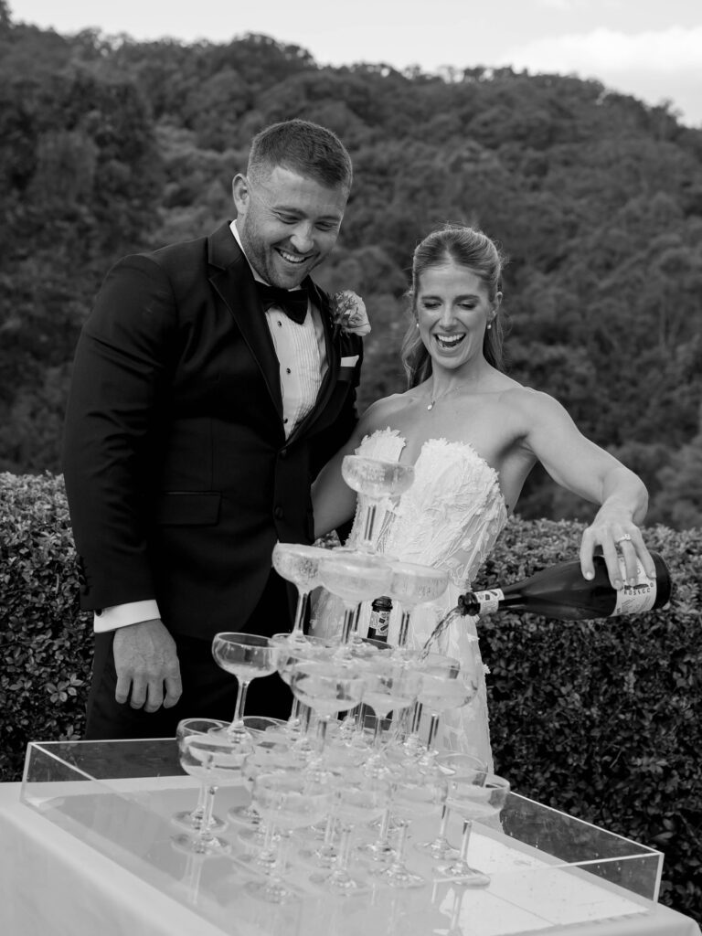 happy couple pouring champagne tower after outdoor sunshine coast wedding ceremony