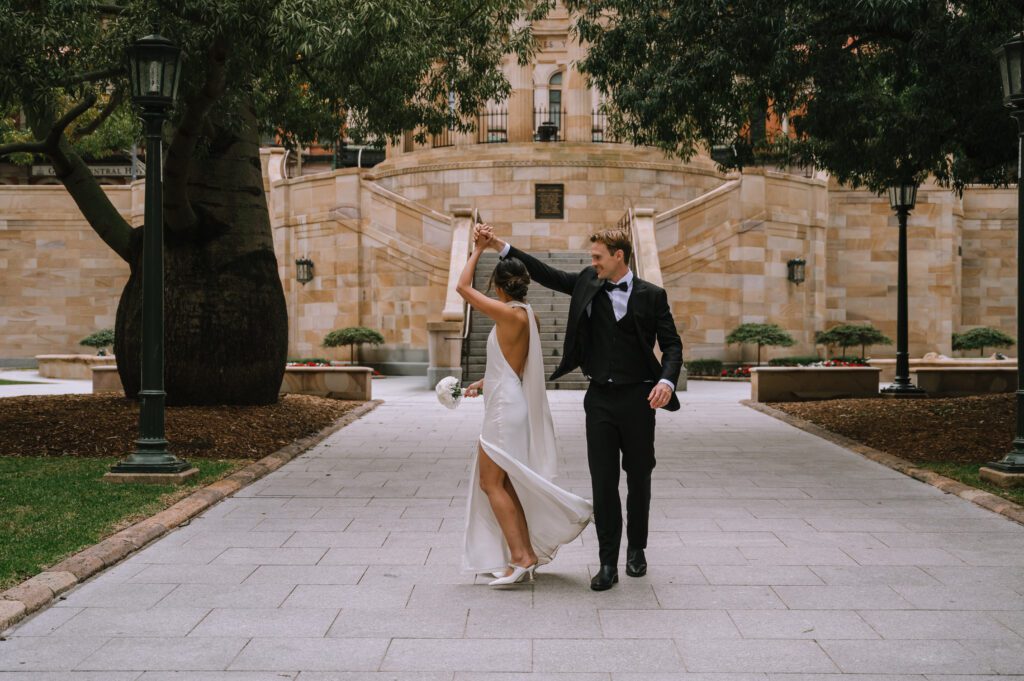 groom twirling bride during couple portraits in the park after elopement ceremony in brisbane