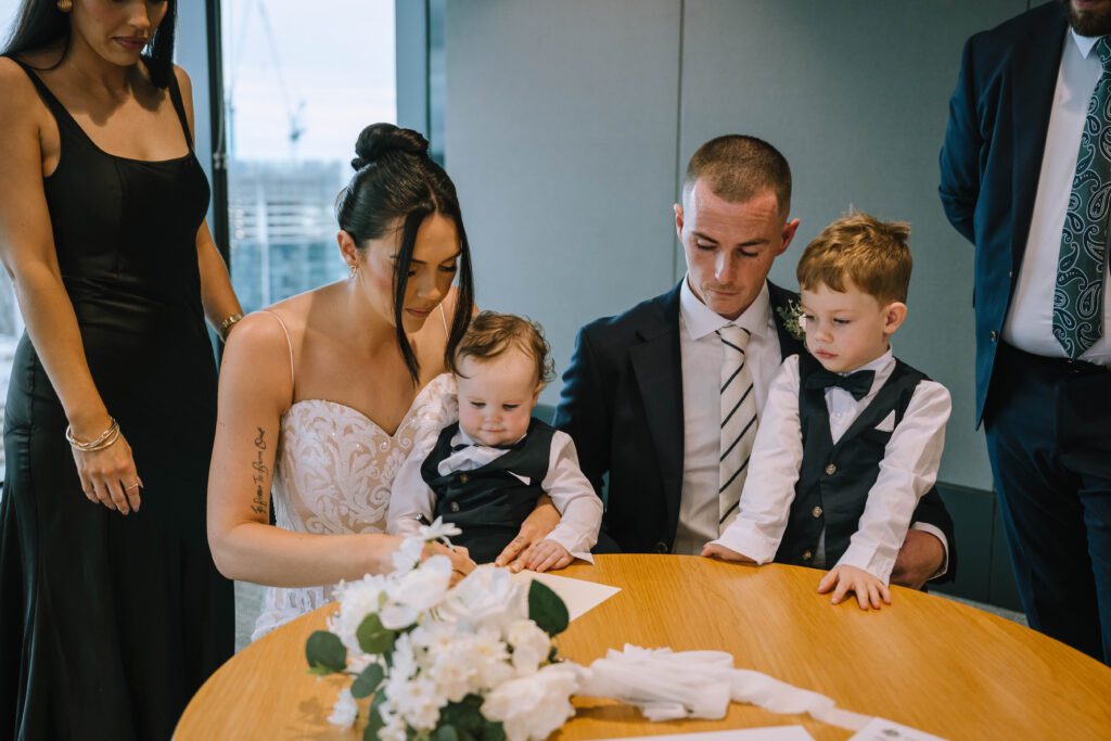 couple signing paperwork with their kids during their elopement ceremony at brisbane registry