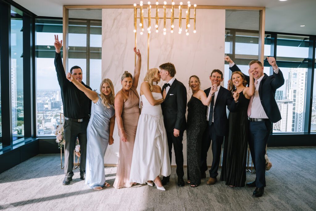 couple kissing as family celebrates during intimate brisbane registry elopement