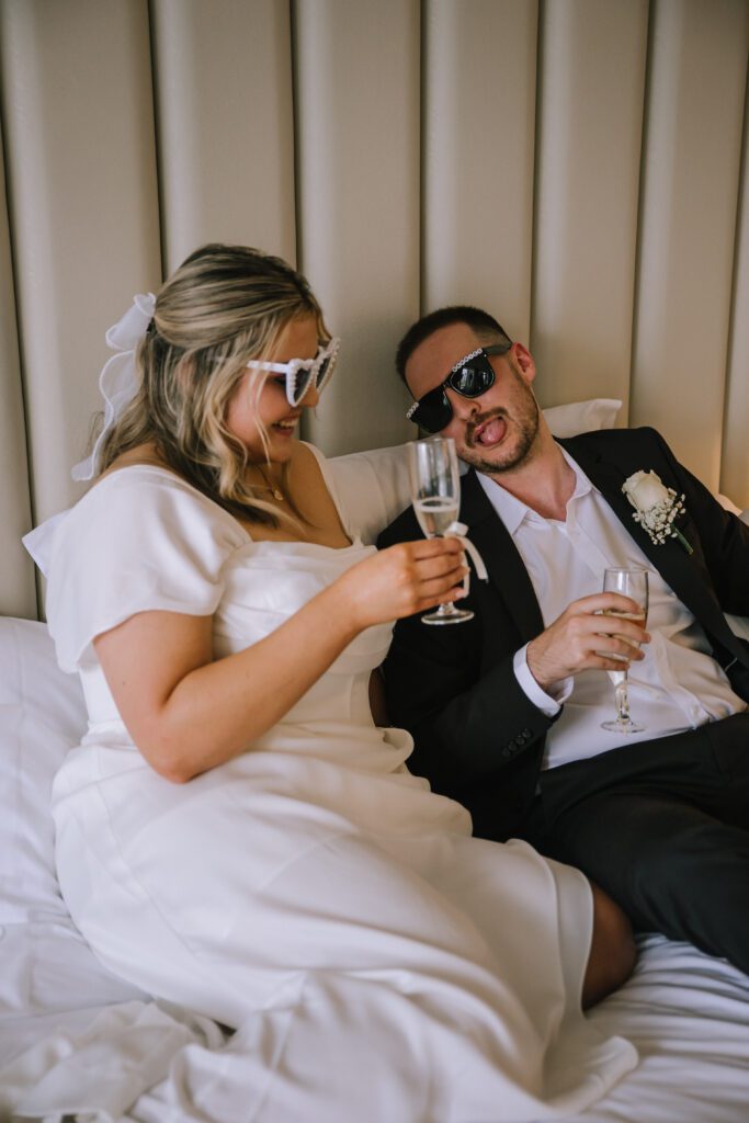 couple drinking champagne in bed before eloping at emporium hotel southbank
