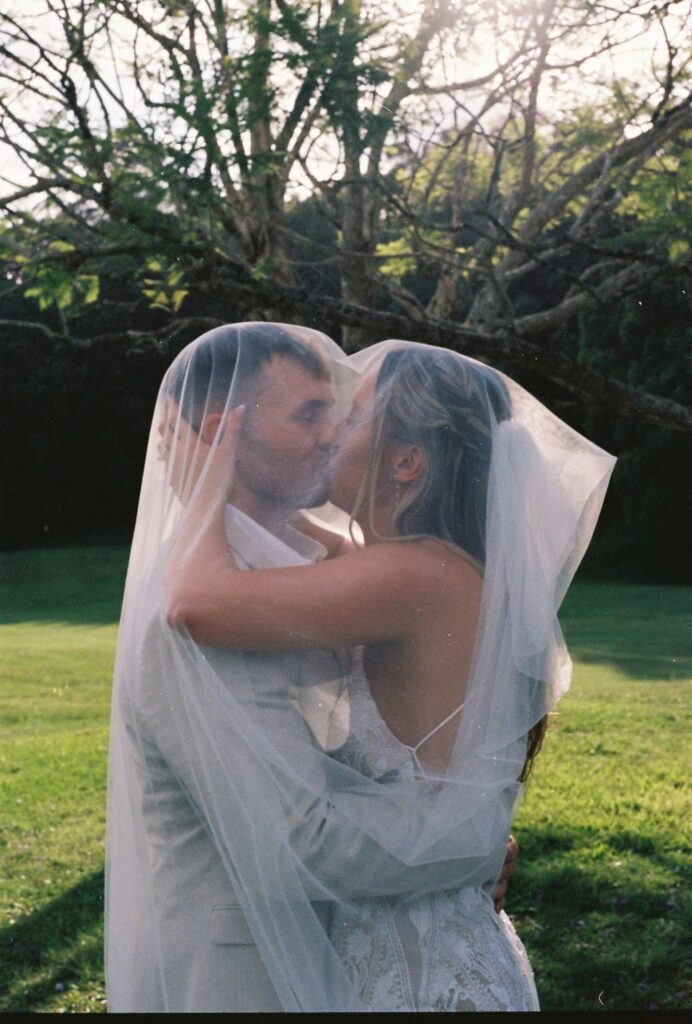 cinematic shot of coupe kissing under bride's veil captured on 35mm film format 