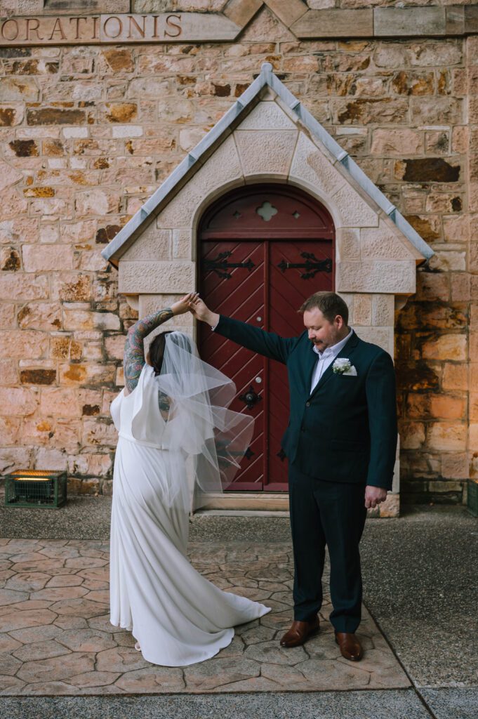 groom twirling bride outside the inchcolm hotel wedding venue in brisbane