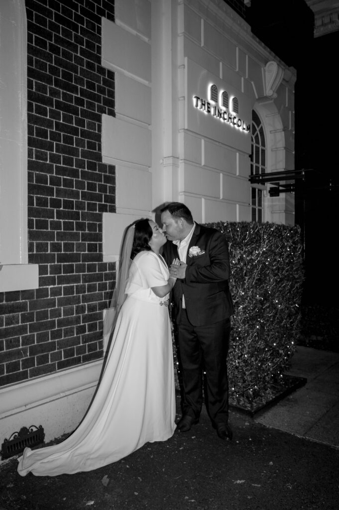 black and white shot of couple kissing outside the inchcolm hotel in spring hill brisbane
