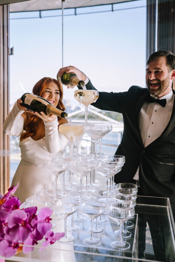 couple pouring champagne tower during wedding reception at w brisbane hotel in cbd