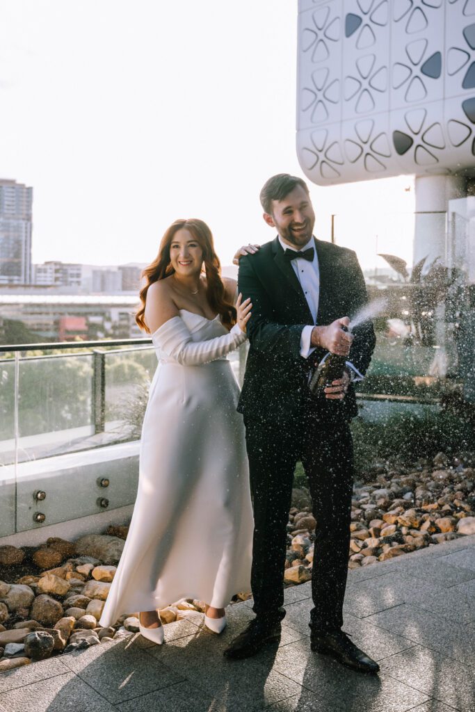 couple doing champagne spray on the rooftop at w brisbane hotel wedding venue