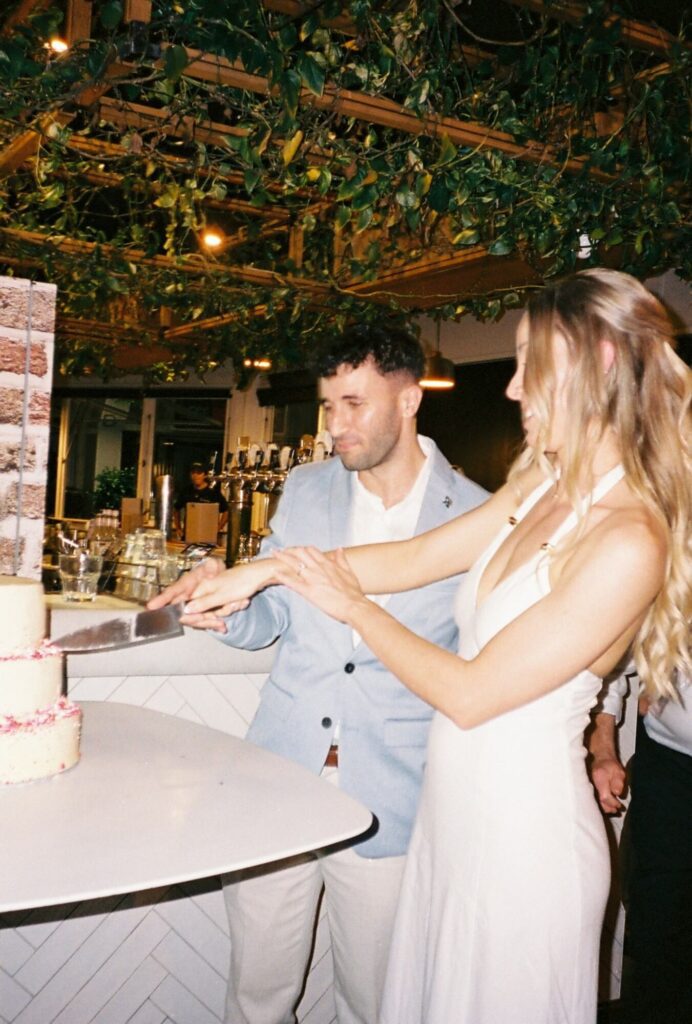 candid shot of couple cutting cake during engagement party on 35mm film medium 