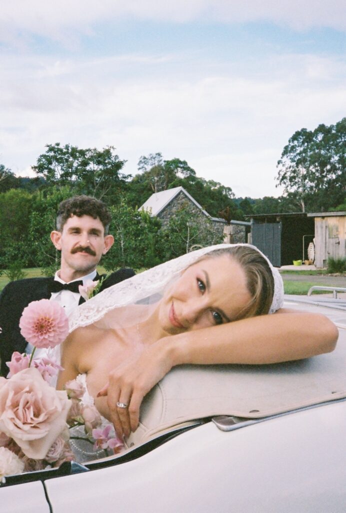 editorial wedding portrait of couple sitting in vintage car captured on 35mm film 