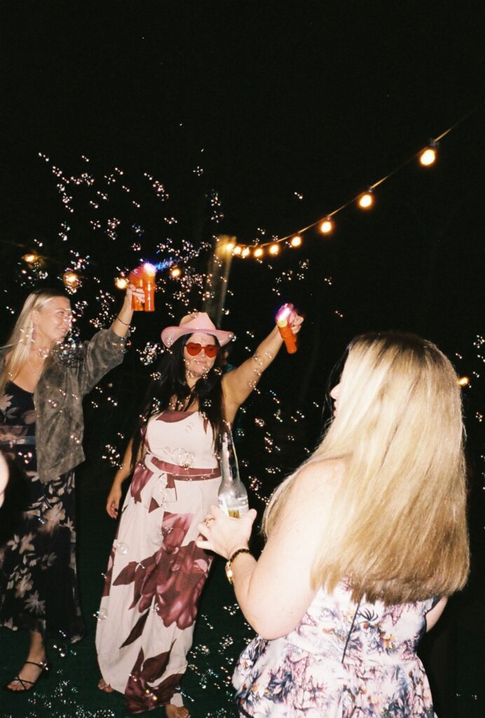 guests celebrating with soap bubble guns during wedding reception captured on 35mm film 