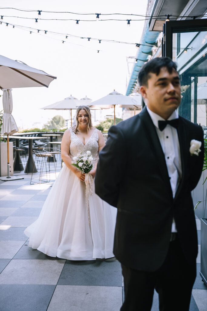 bride approaching groom from behind during first look at Crystalbrook Hotel