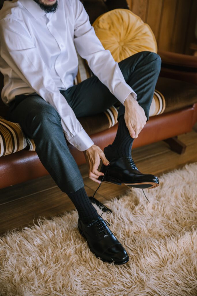 groom putting on shoes during getting ready before wedding ceremony