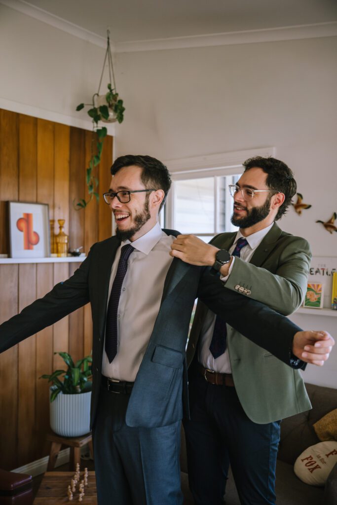 best man helping the groom put on his blazer during getting ready moments