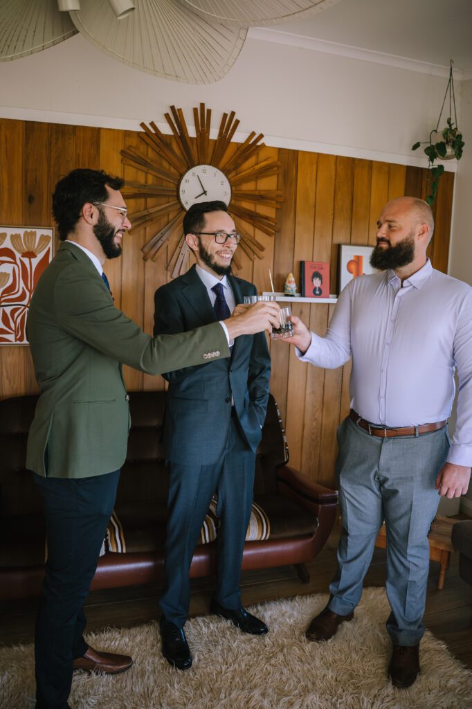 groom enjoying drinks with his groomsmen during morning prep before the wedding ceremony