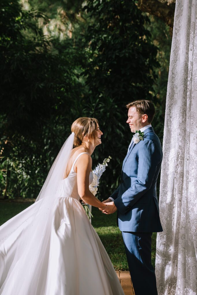 bride and groom beaming at each other as they hold hands for the first time during wedding ceremony