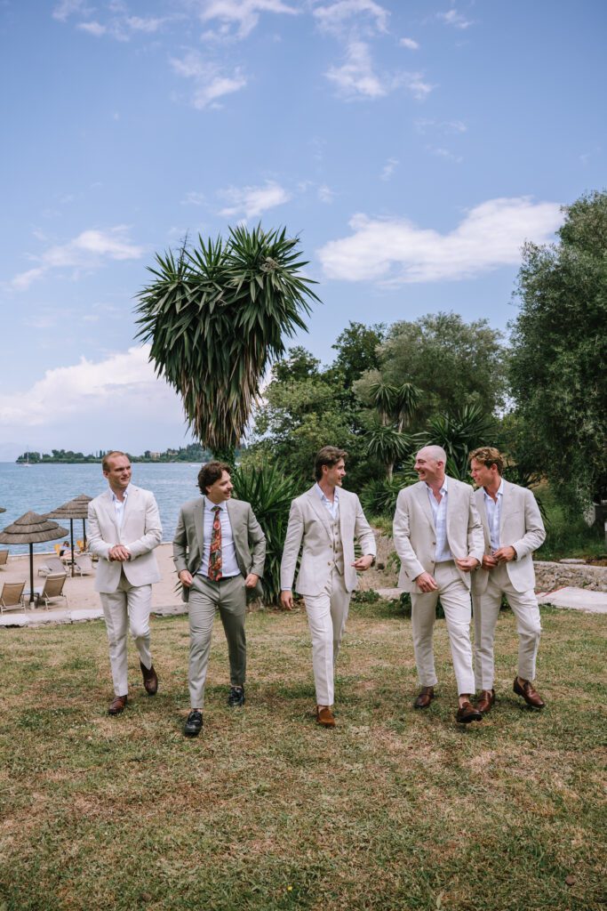 groom and wedding party walking towards wedding ceremony location at Hyatt Ziva Corfu with beach in the background