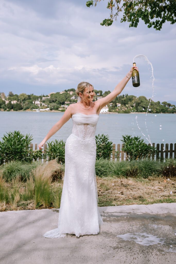candid shot of bride popping champagne bottle before destination wedding ceremony at Hyatt Ziva Corfu