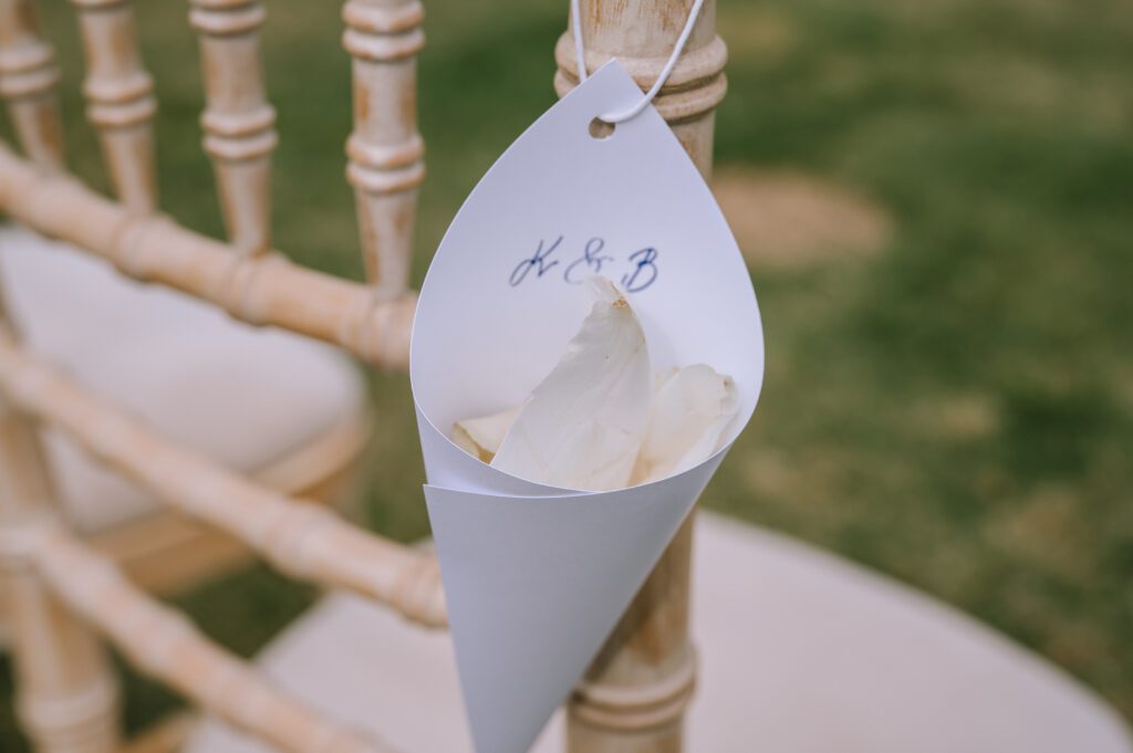 close up of flower petal confetti in paper cones personalised with the couples initials for wedding ceremony