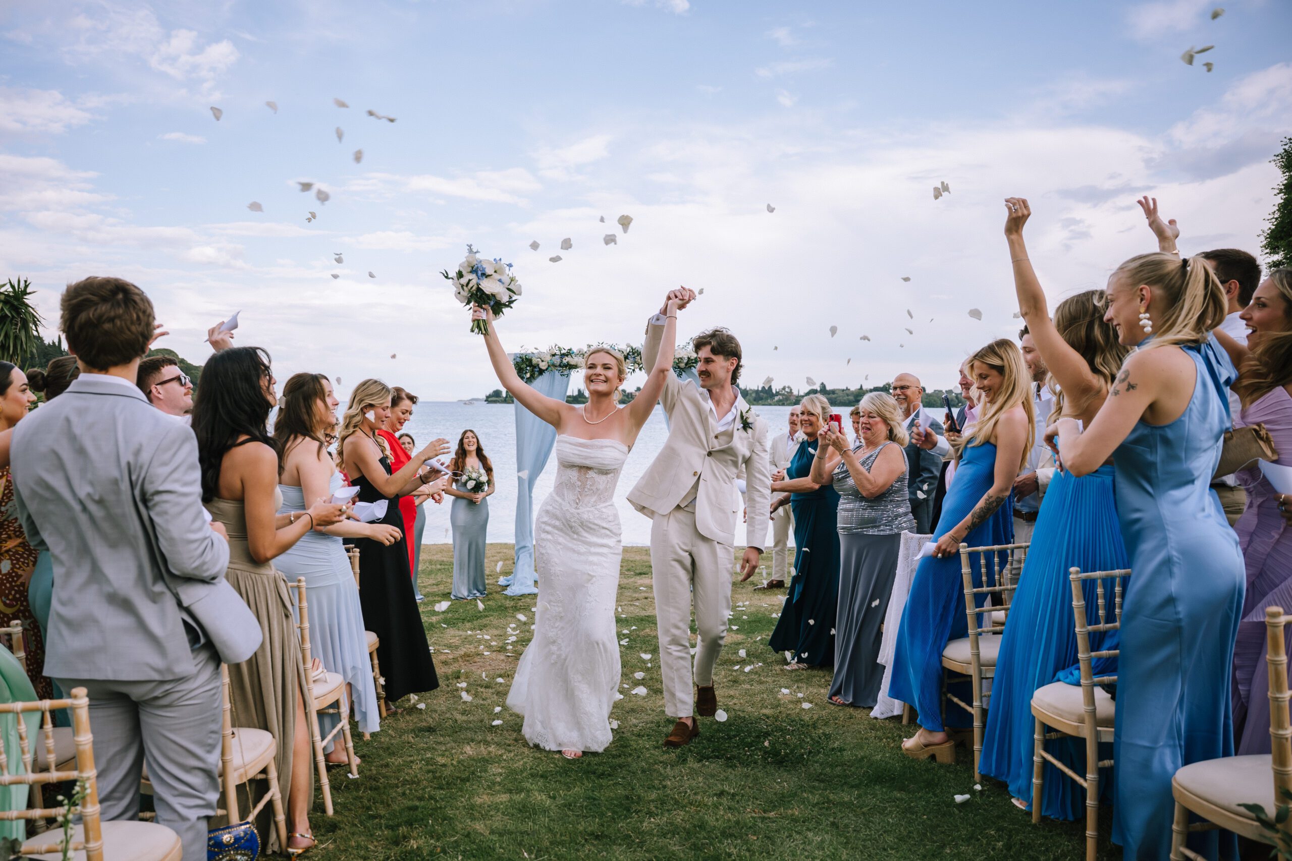 candid portrait of couple walking back down the aisle celebrating with their arms in the air as guests throw confetti
