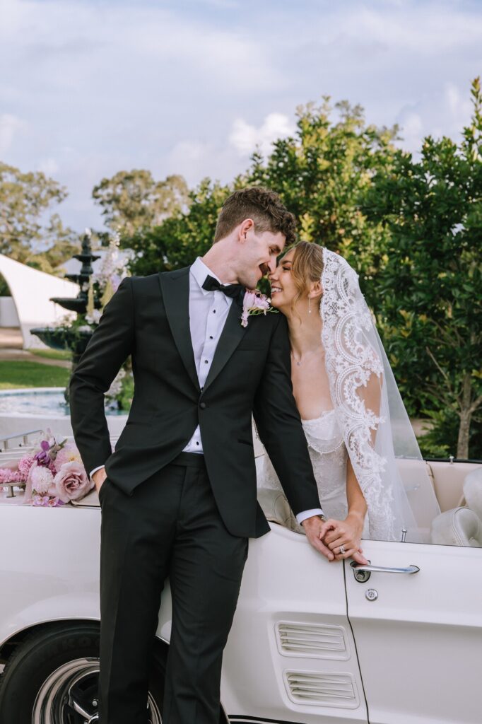 editorial portrait of couple posing with vintage car at goodwater ridge wedding venue