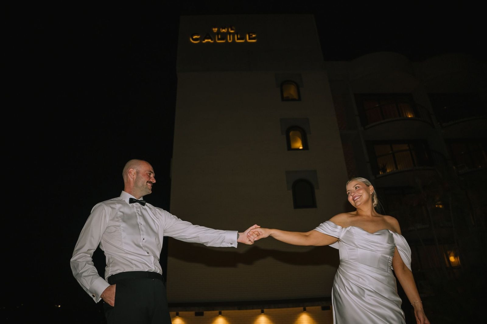 flash photography of bride and groom holding hands from below outside the calile hotel