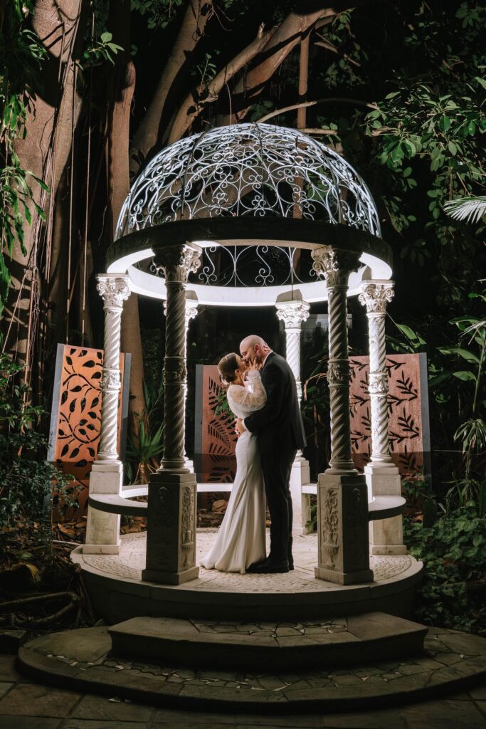 stunning night portrait of couple kissing under lit up monument