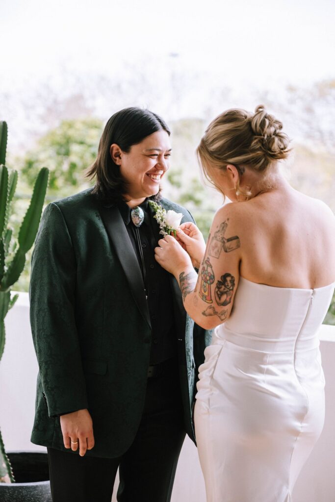 bride adjusting bride's boutonniere during first look